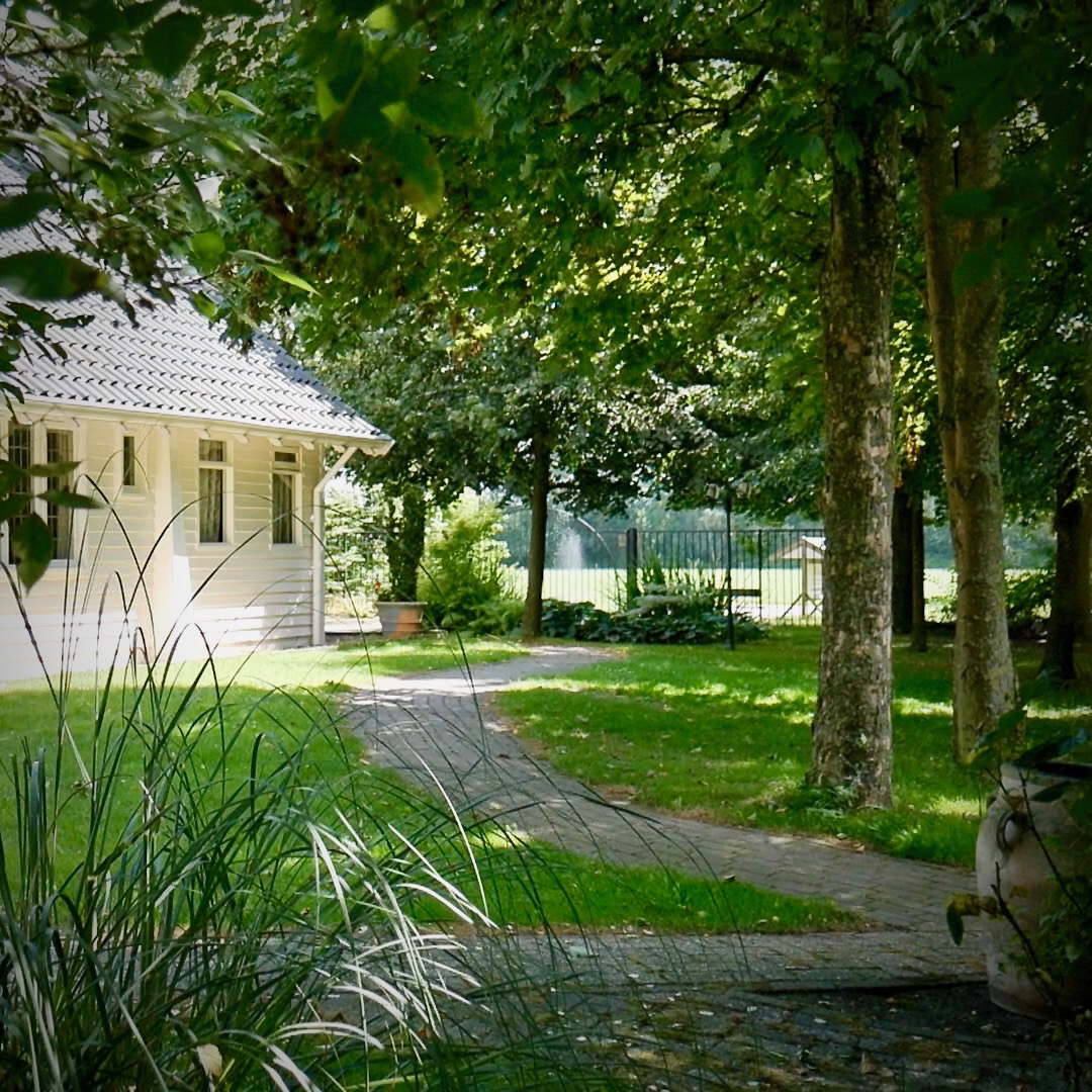 Sfeervolle tuinpaden bij Wit Kerkje omringd door oude bomen