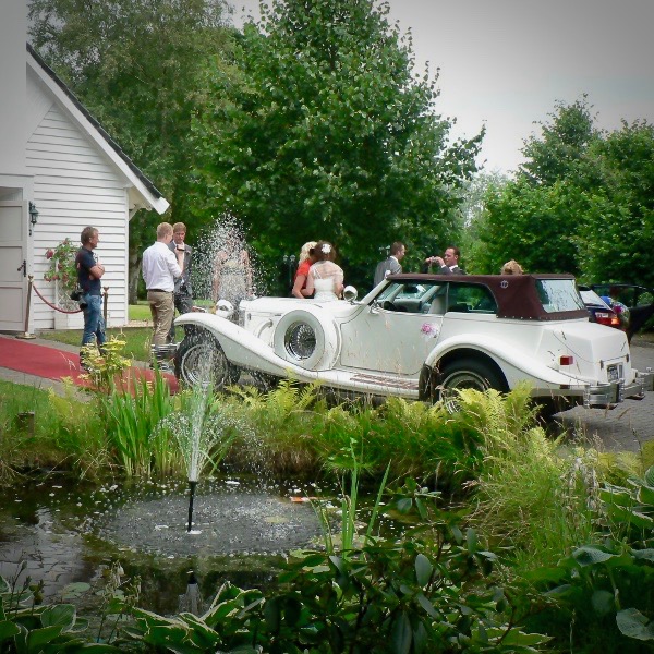 Bruidspaar met klassieke trouwauto bij Wit Kerkje - perfecte trouwlocatie